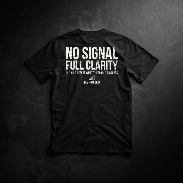 An image of the back of a black t-shirt featuring a distressed white typography design. The main text reads "NO SIGNAL FULL CLARITY" in a weathered, bold sans-serif font. Below it, a smaller tagline states, "THE WILD RESETS WHAT THE WORLD DISTORTS," positioned above a minimalist cell signal bar icon with a strike-through. The brand branding "SXA • OFF GRID" is printed at the bottom. The shirt is laid flat on a dark, textured stone background, catering to off-grid living, camping, and outdoor adventure enthu