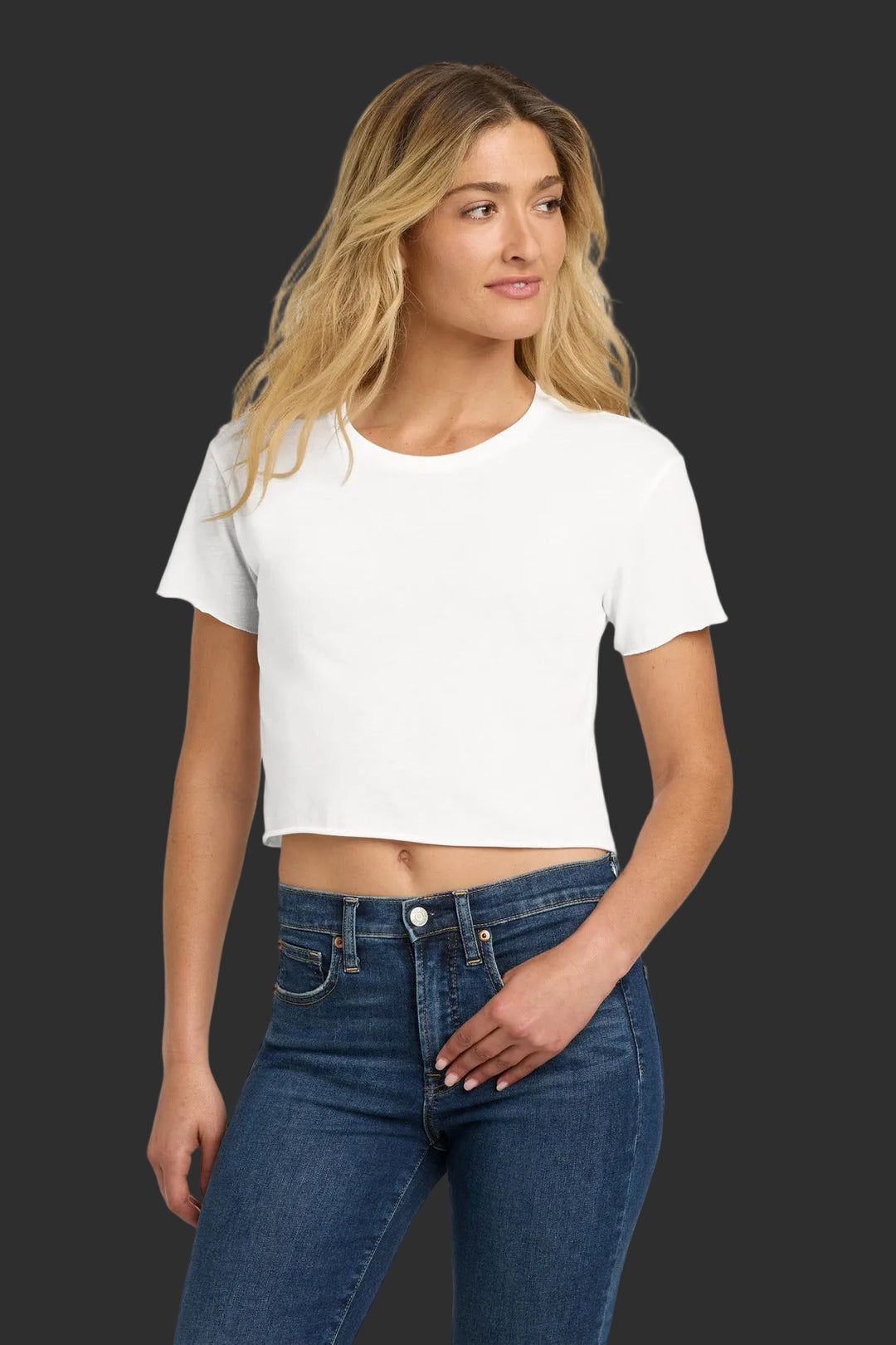 Woman wearing a white crop top and blue jeans on a white background